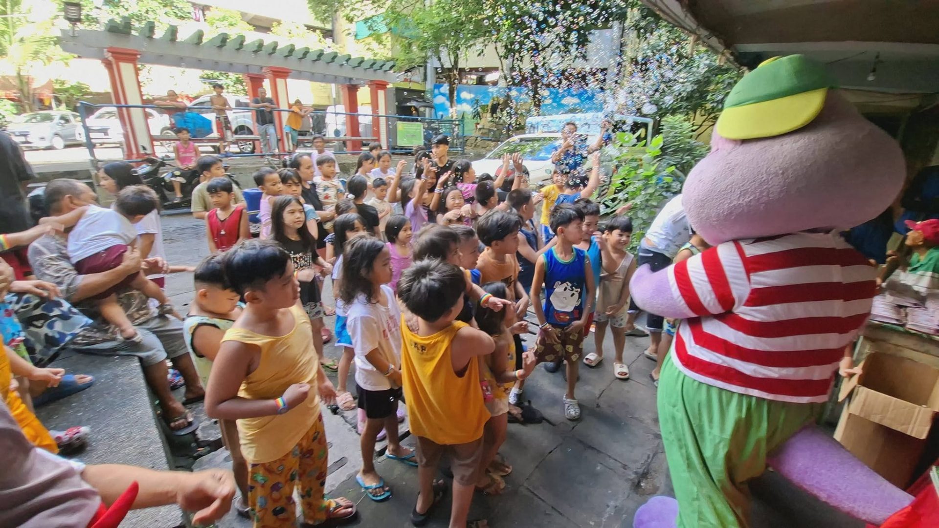 Children watching a costumed mascot in a courtyard