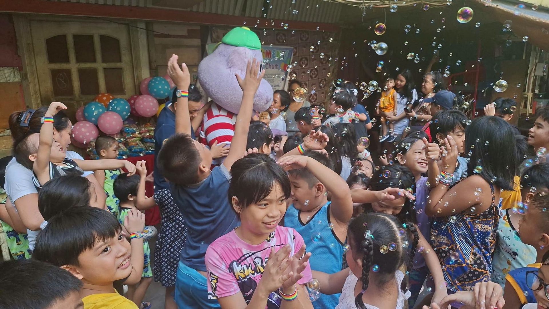 Children laughing and reaching for bubbles at a celebration